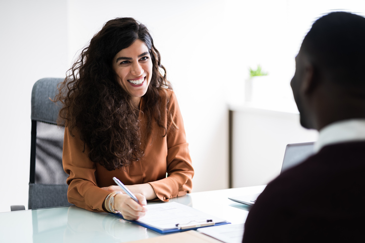 Recruiter smiling across a desk during interview with a candidate